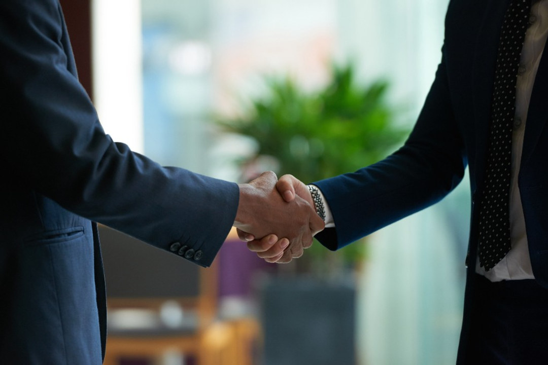 Close-up of two business professionals in suits shaking hands, representing trusted partnership